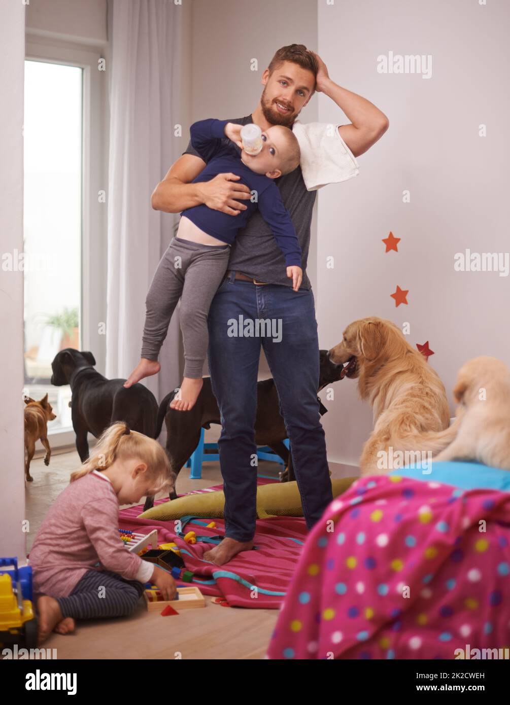 Das ist zu viel. Ein überwältigter Vater, umgeben von seinen Kindern und Hunden. Stockfoto