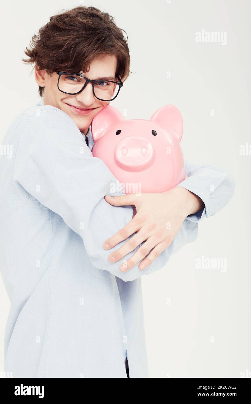 Ich bin ach so vorsichtig mit meinem Geld. Porträt eines jungen Mannes, der ein Sparschwein eng an sich umarmt. Stockfoto