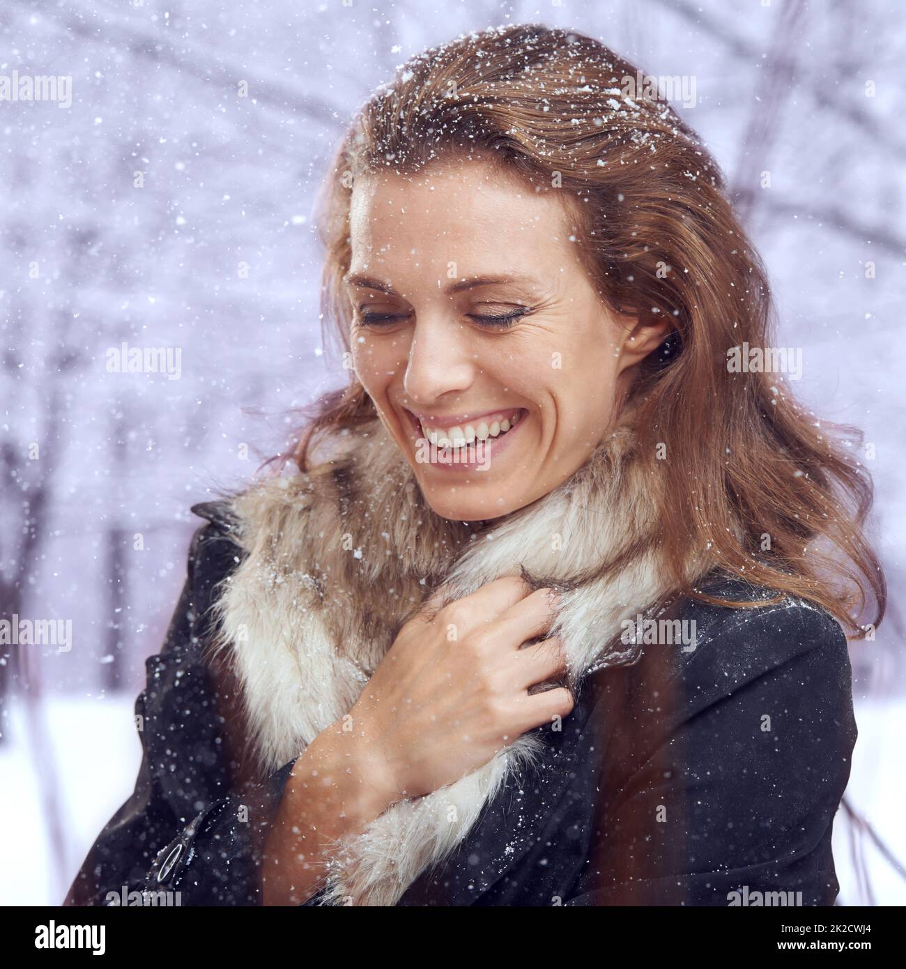 Ein Moment der Wärme. Aufnahme einer attraktiven Frau, die im Schnee lächelt. Stockfoto