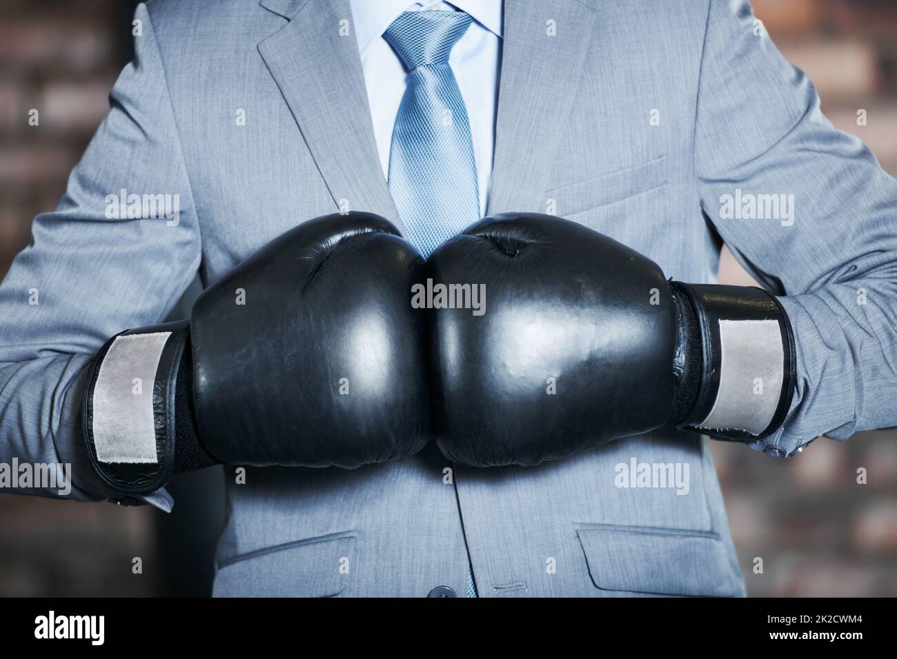 Die Hölle kämpft sich an die Spitze. Ein Mann in einem Anzug, der seine Boxhandschuhe zusammenstanzt. Stockfoto