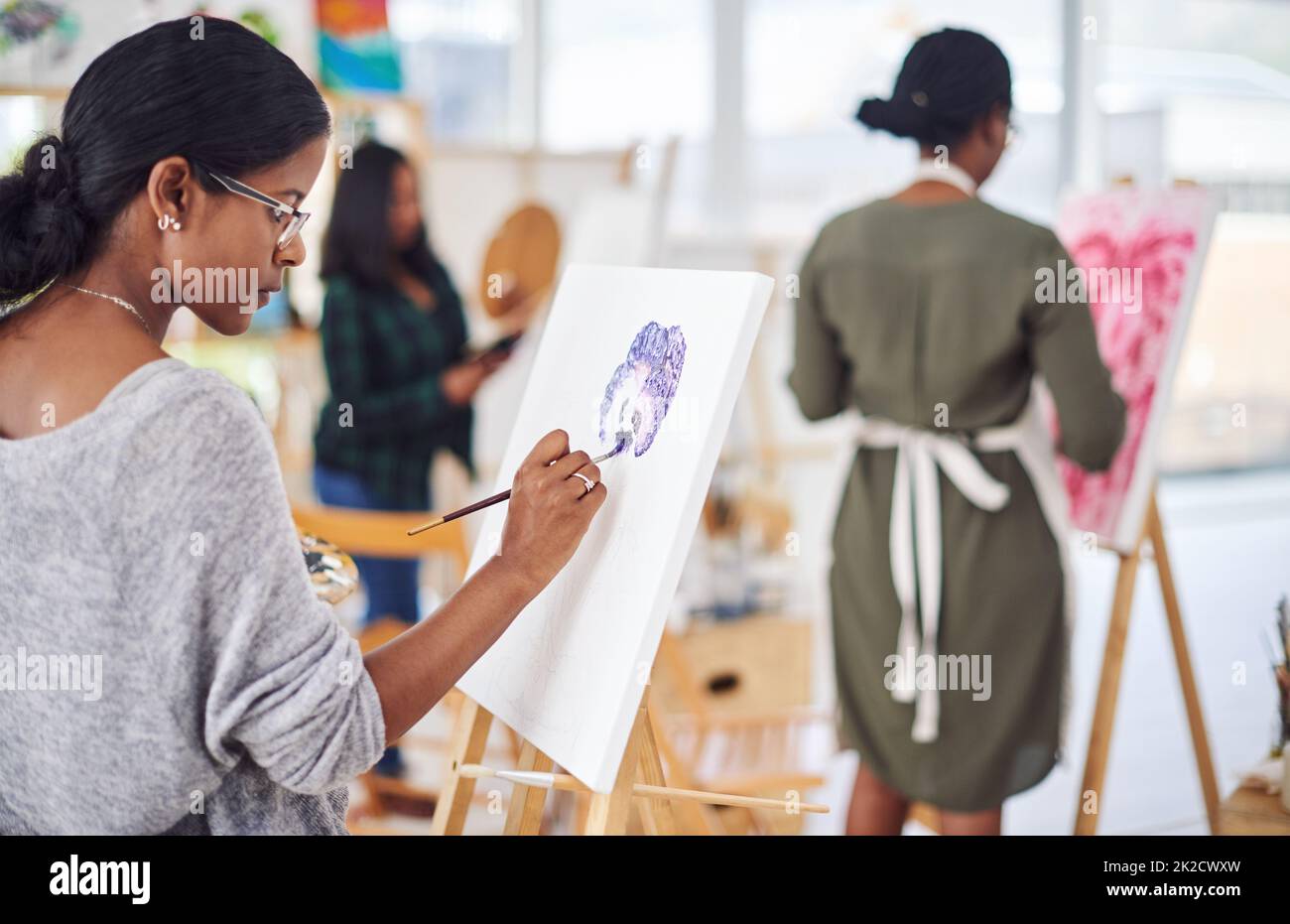 Genießen Sie eine weitere Kunstsitzung. Defokussieren einer Gruppe von Menschen, die in einem Kunststudio malen. Stockfoto