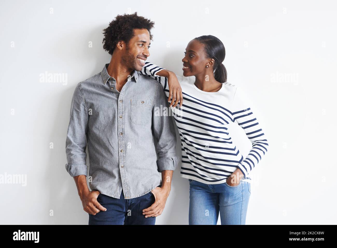 Absolut verführt. Ein glückliches junges Paar, das liebevoll an einer weißen Wand zusammensteht. Stockfoto