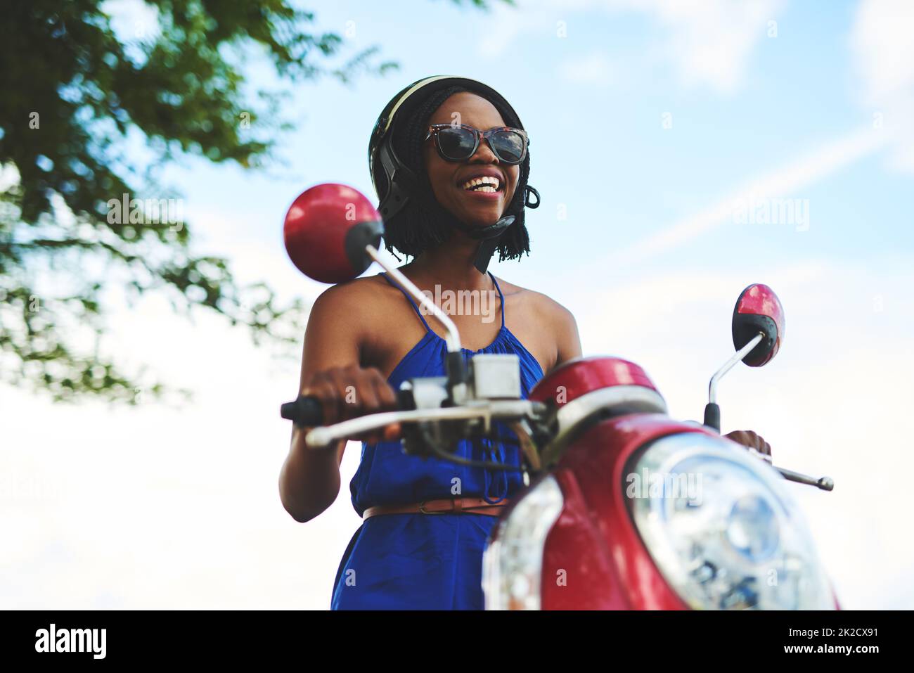 Mein Roller und ich. Aufnahme einer glücklichen jungen Frau, die alleine auf einen Motorroller fahren wollte. Stockfoto