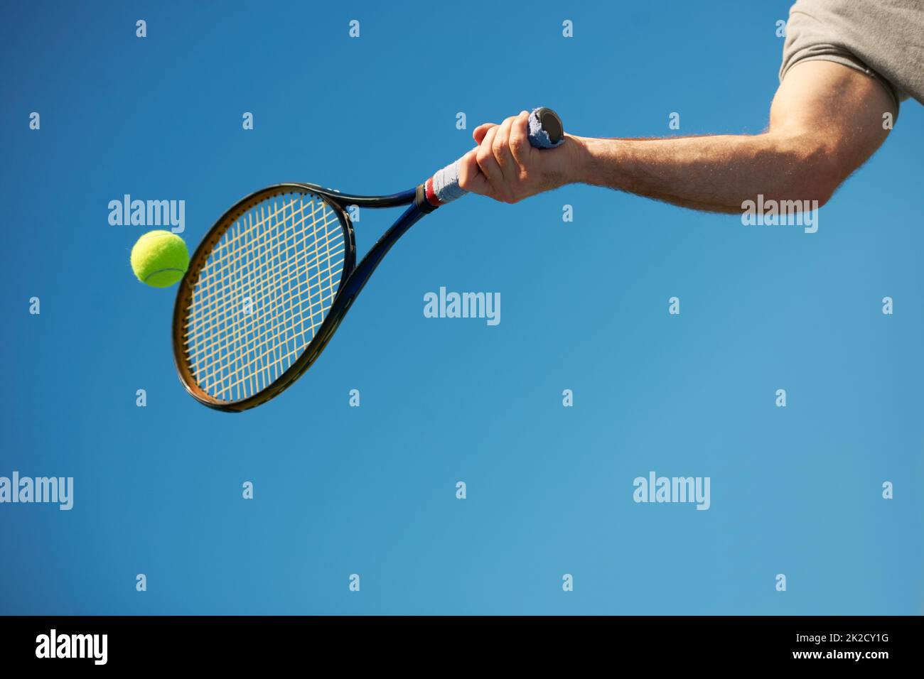 Und zurück. Aufnahme eines Arms, der mit einem Schläger auf einen Tennisball trifft. Stockfoto