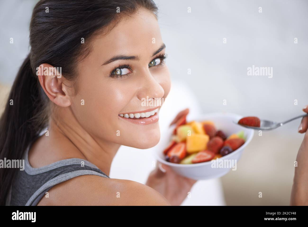Mein gesunder Snack. Eine junge Frau, die eine Schüssel mit gehacktem Obst isst. Stockfoto