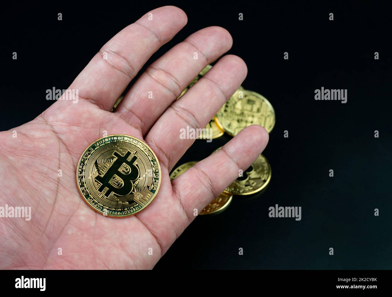 bitcoin-Münze auf der Hand auf schwarzem Hintergrund platziert Stockfoto