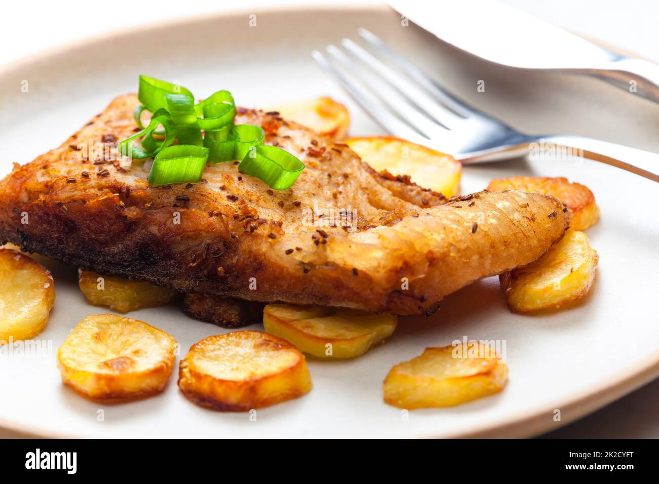 Karpfen auf Kreuzkümmel mit gebratenen Kartoffeln Stockfoto