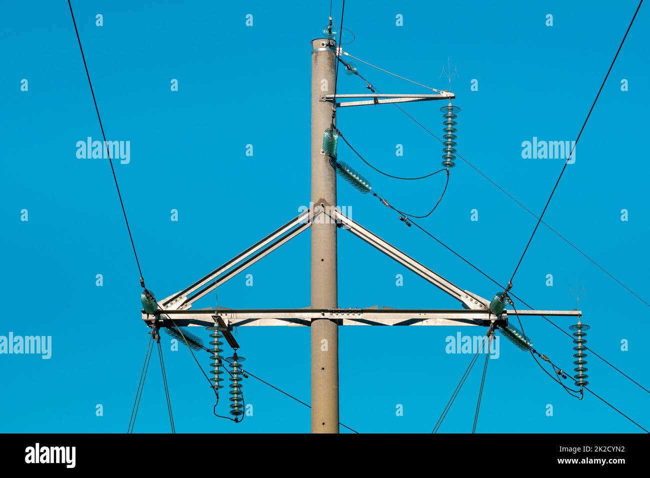 Strommasten, elektrische Leitungen und Türme im Hintergrund des blauen Himmels Stockfoto