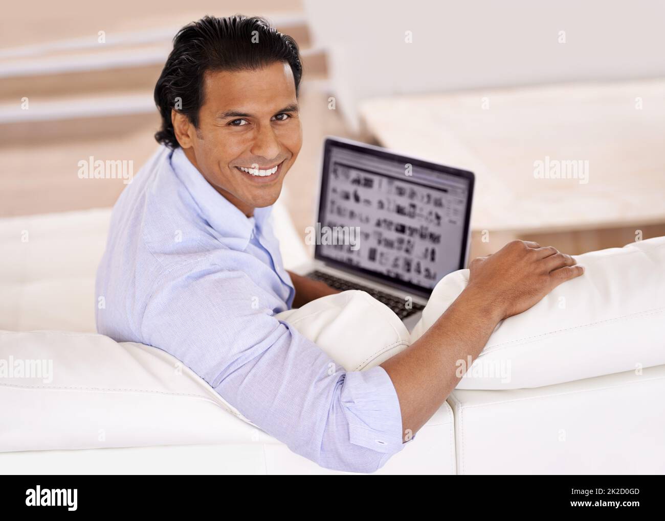 Technologie zu Hause. Ein hübscher junger Mann, der zu Hause seinen Laptop benutzt. Stockfoto