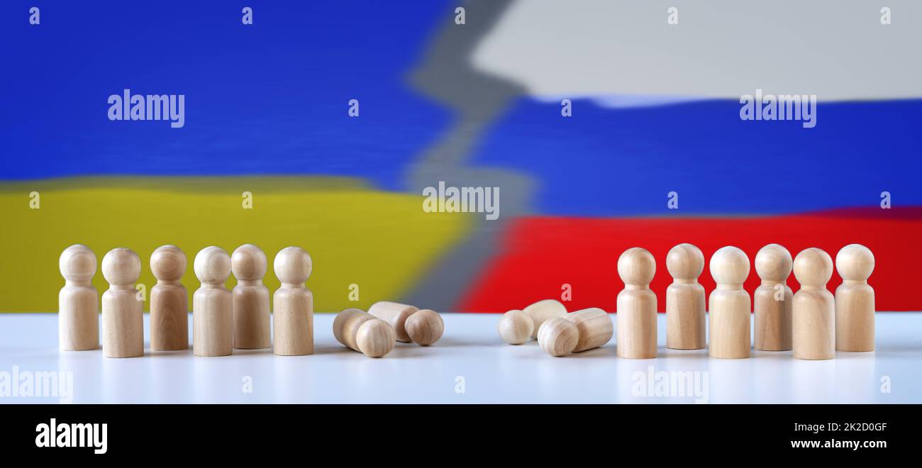 Abstrakte Fotografie mit Figuren von Holzmännern auf dem Hintergrund von Farben der russischen und ukrainischen Fahnen. Stockfoto