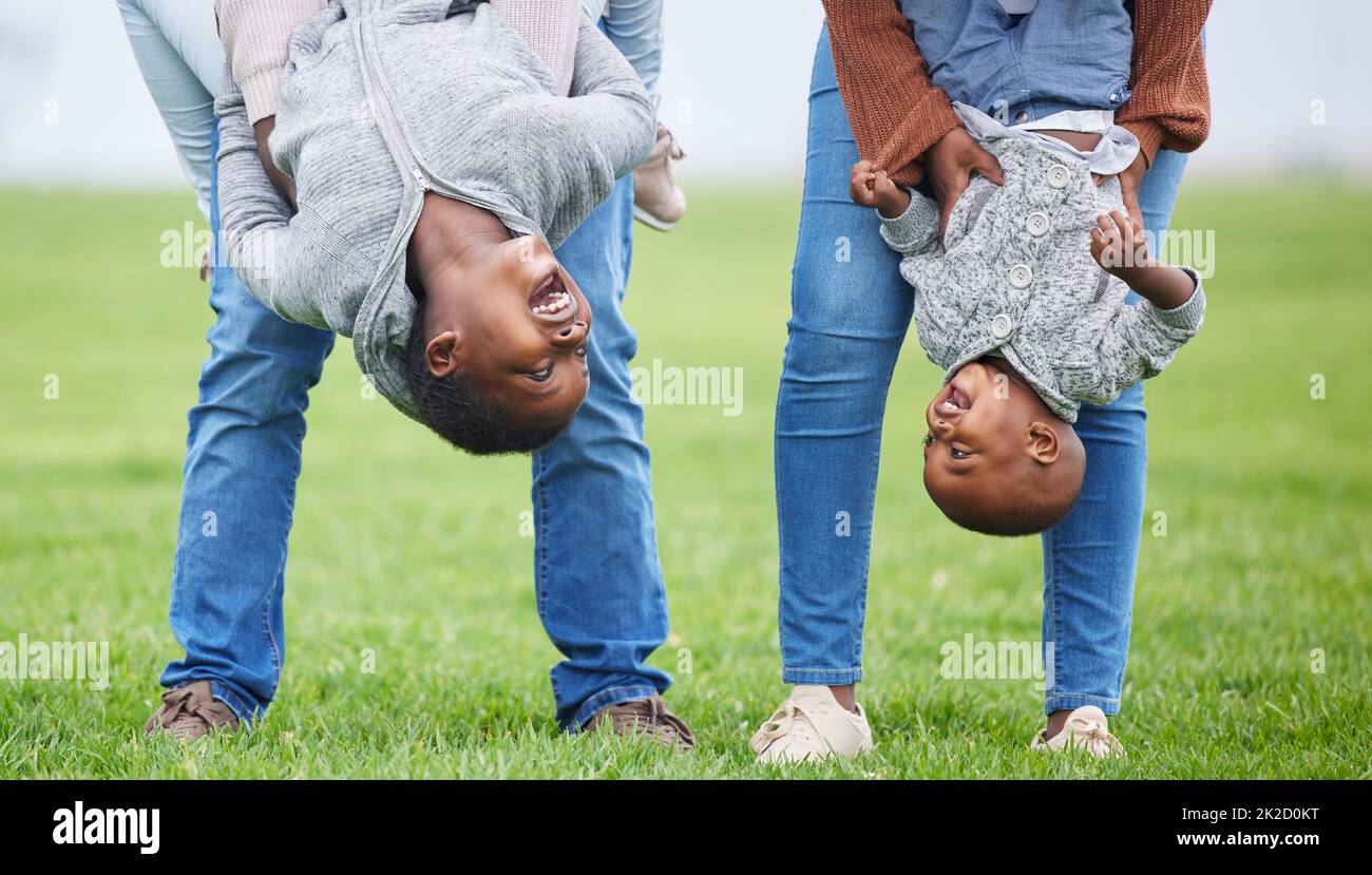 Tun Sie alles, aber lassen Sie es Freude erzeugen. Aufnahme von zwei Kindern, die von ihren Eltern draußen auf dem Kopf hängen. Stockfoto