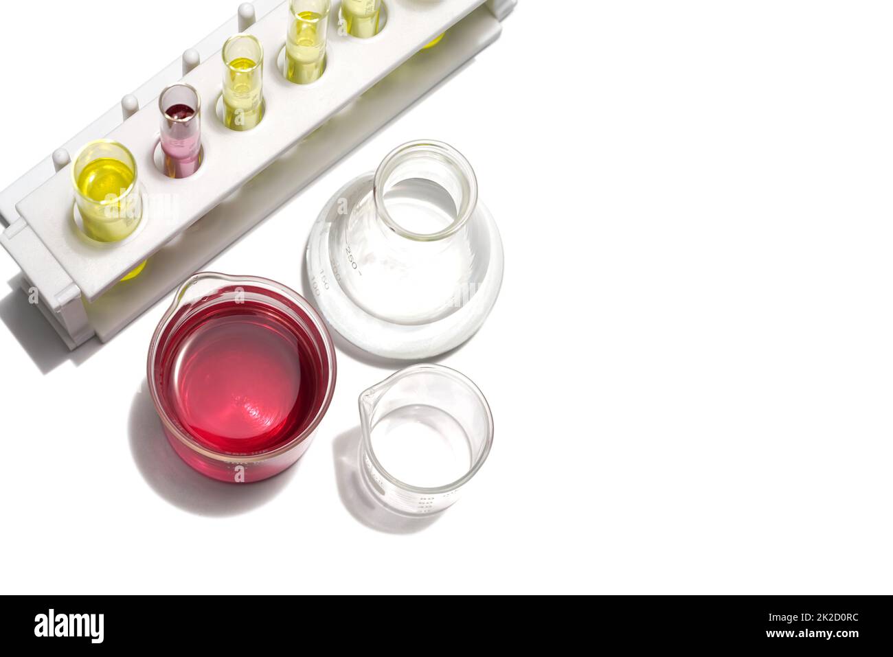 Kaliumpermanganat Flüssigkeit im Becher und Alkohol im Erlenmeyerkolben Platz neben dem Reagenzglasständer mit gelber kosmetischer Farbe (Öl). Stockfoto