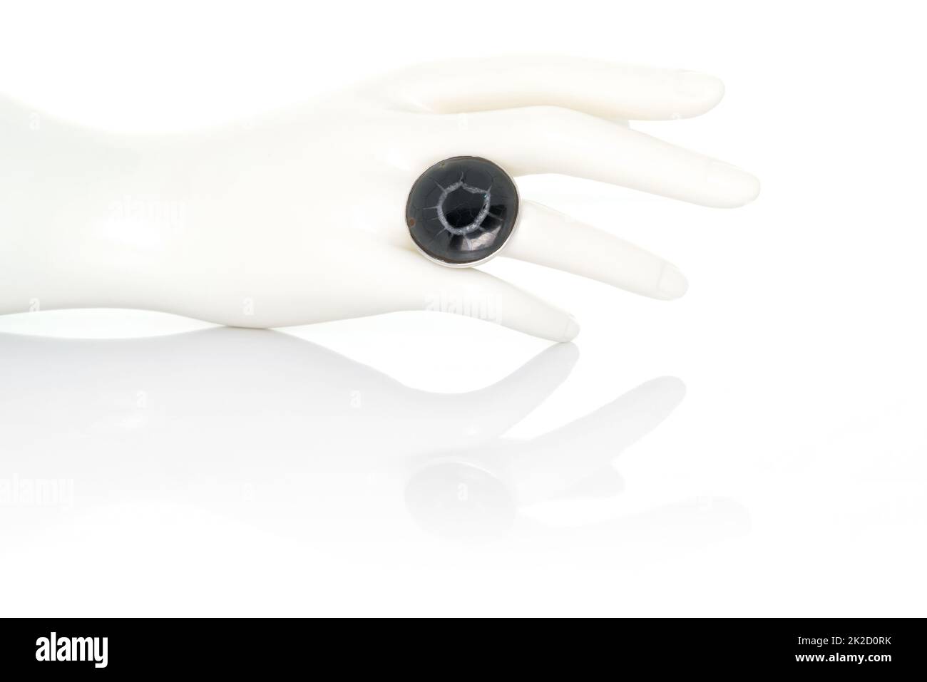 Schwarzer Fossil Mud Crack Stone Cabochon Ring auf Kunststoff-Schaufensterpuppe weibliche Hand. Kollektion von natürlichen Edelsteinen Accessoires. Studioaufnahme Stockfoto