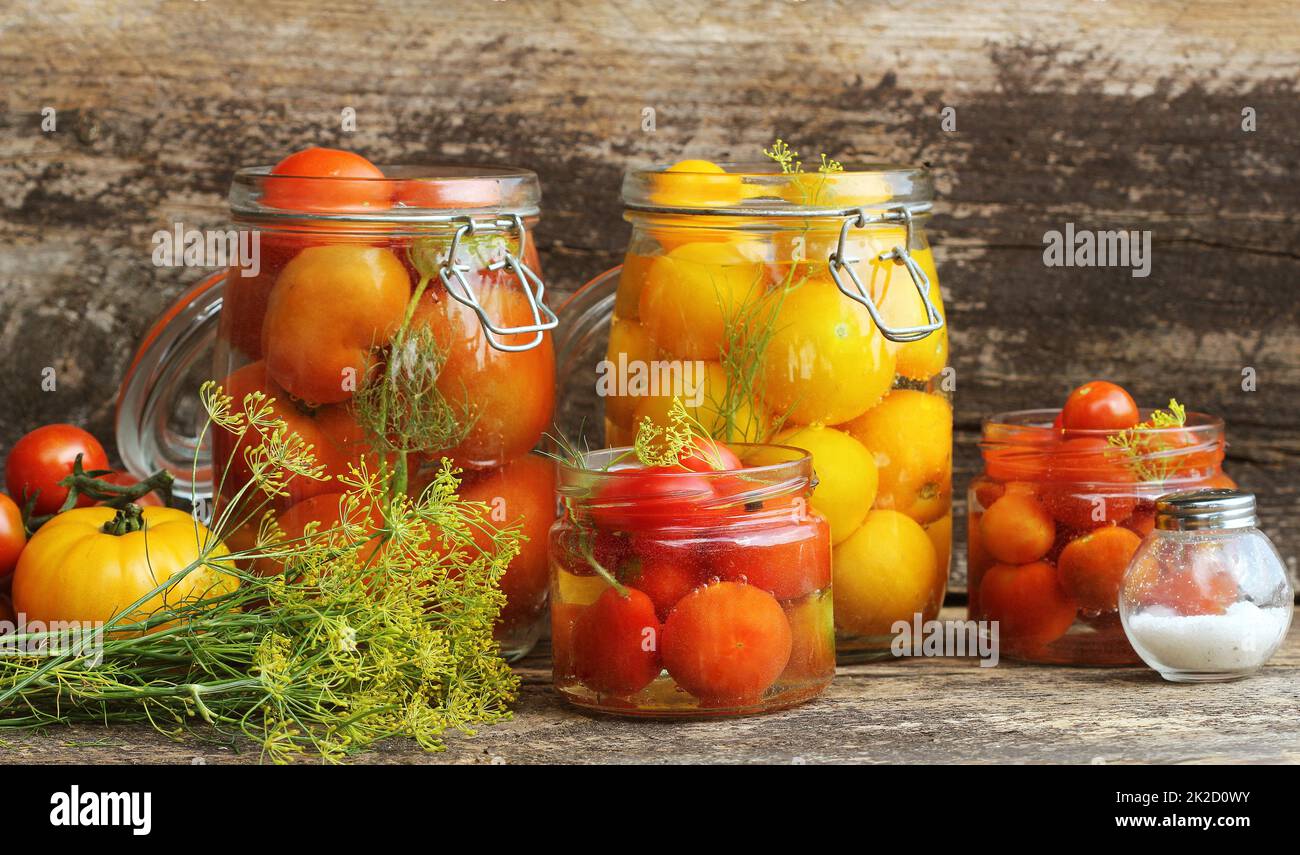 Eingelegte Tomaten in Töpfen auf hölzernen Tisch. Tomaten fermentiert Prozess Gläsern Vielfalt - rot, gelb, orange Stockfoto