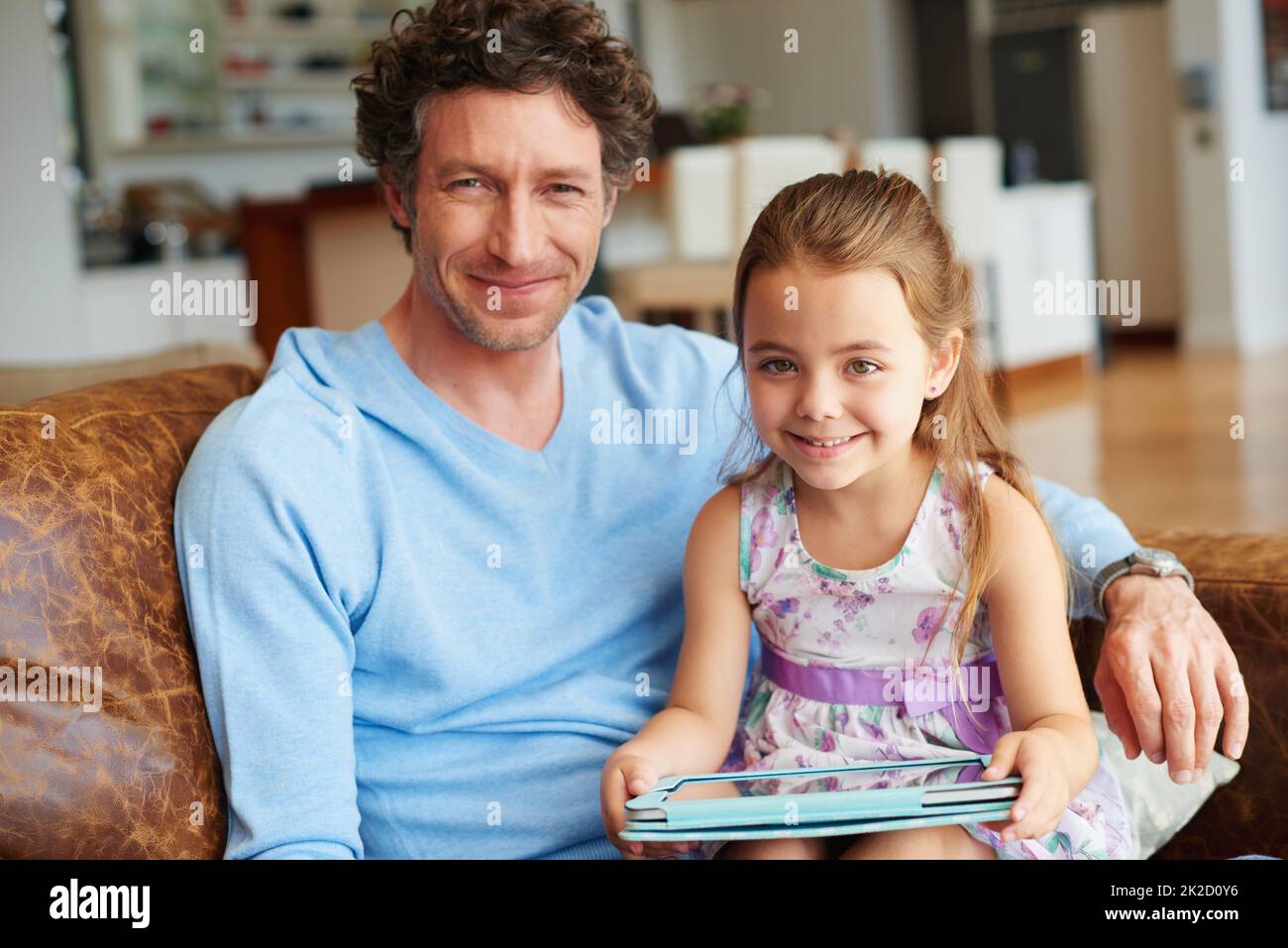 Entdecken Sie die digitale Welt mit Papa. Ein kleines Mädchen und ihr Vater mit einem digitalen Tablet zu Hause. Stockfoto