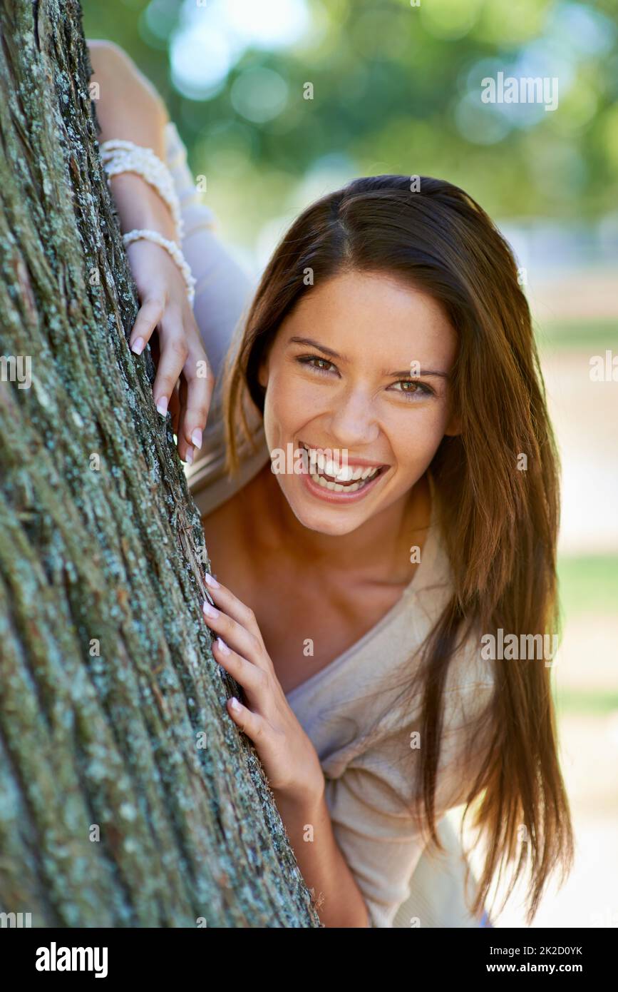Frei, ich selbst zu sein. Porträt einer schönen jungen Frau, die hinter einem Baum im Park steht. Stockfoto