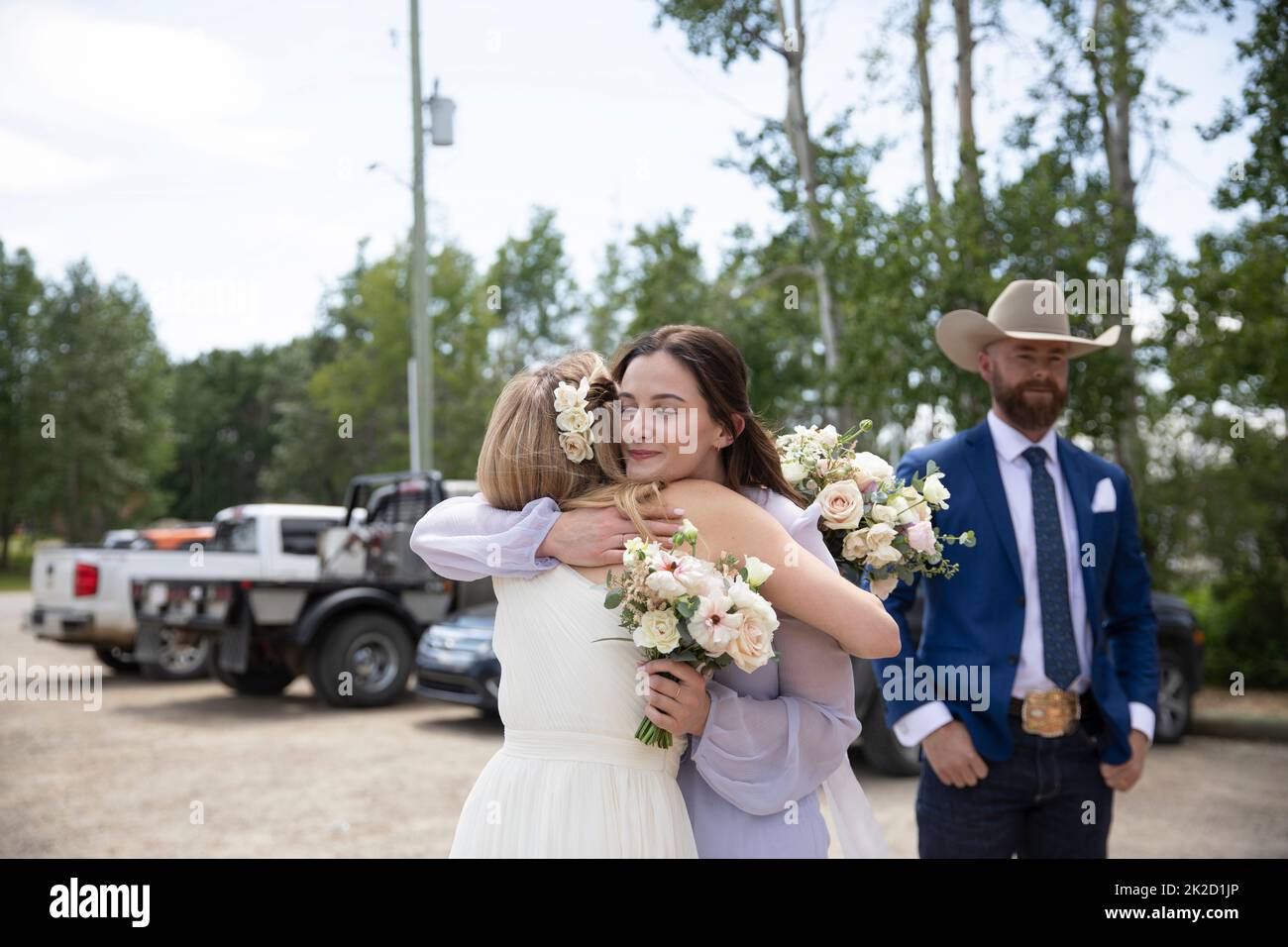 Braut und Dienstmädchen umarmen sich am Hochzeitstag auf dem Parkplatz Stockfoto