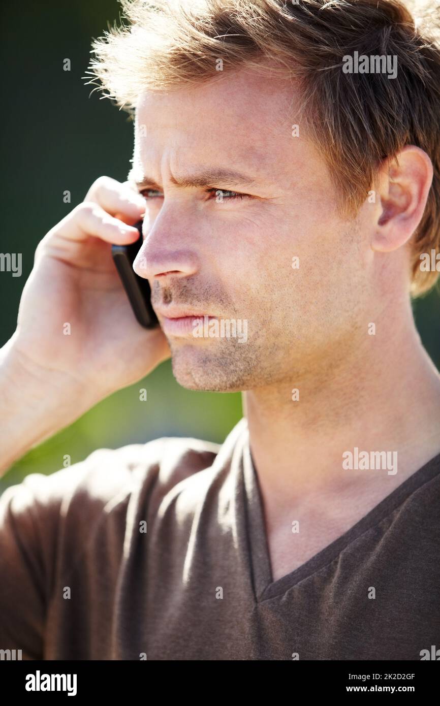 In Verbindung bleiben. Ein hübscher junger Mann, der mit einem ernsten Gesichtsausdruck auf seinem Handy spricht. Stockfoto