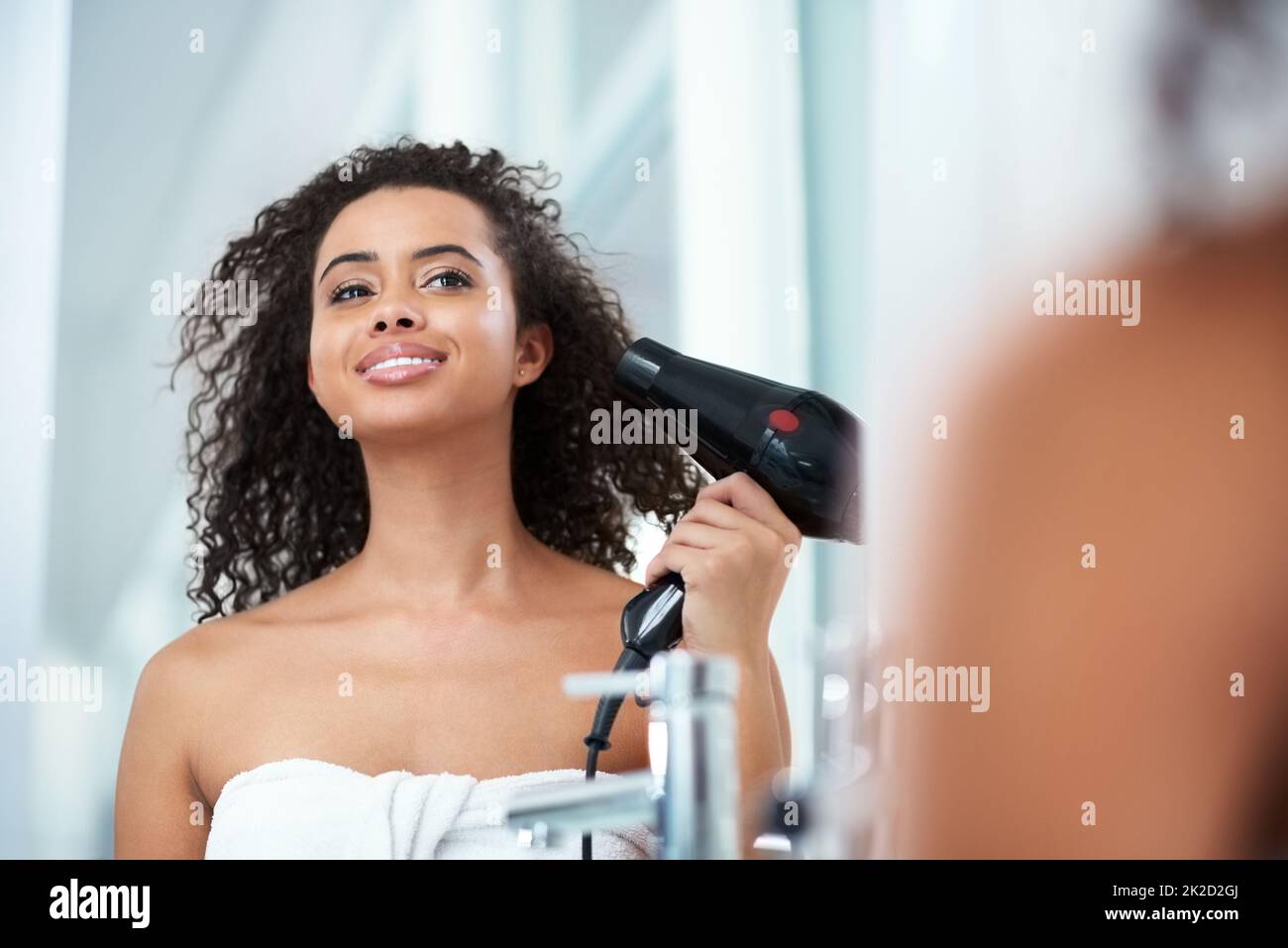 Das Leben ist zu kurz, um langweiliges Haar zu haben. Aufnahme einer attraktiven jungen Frau, die ihre Haare zu Hause trocknet. Stockfoto