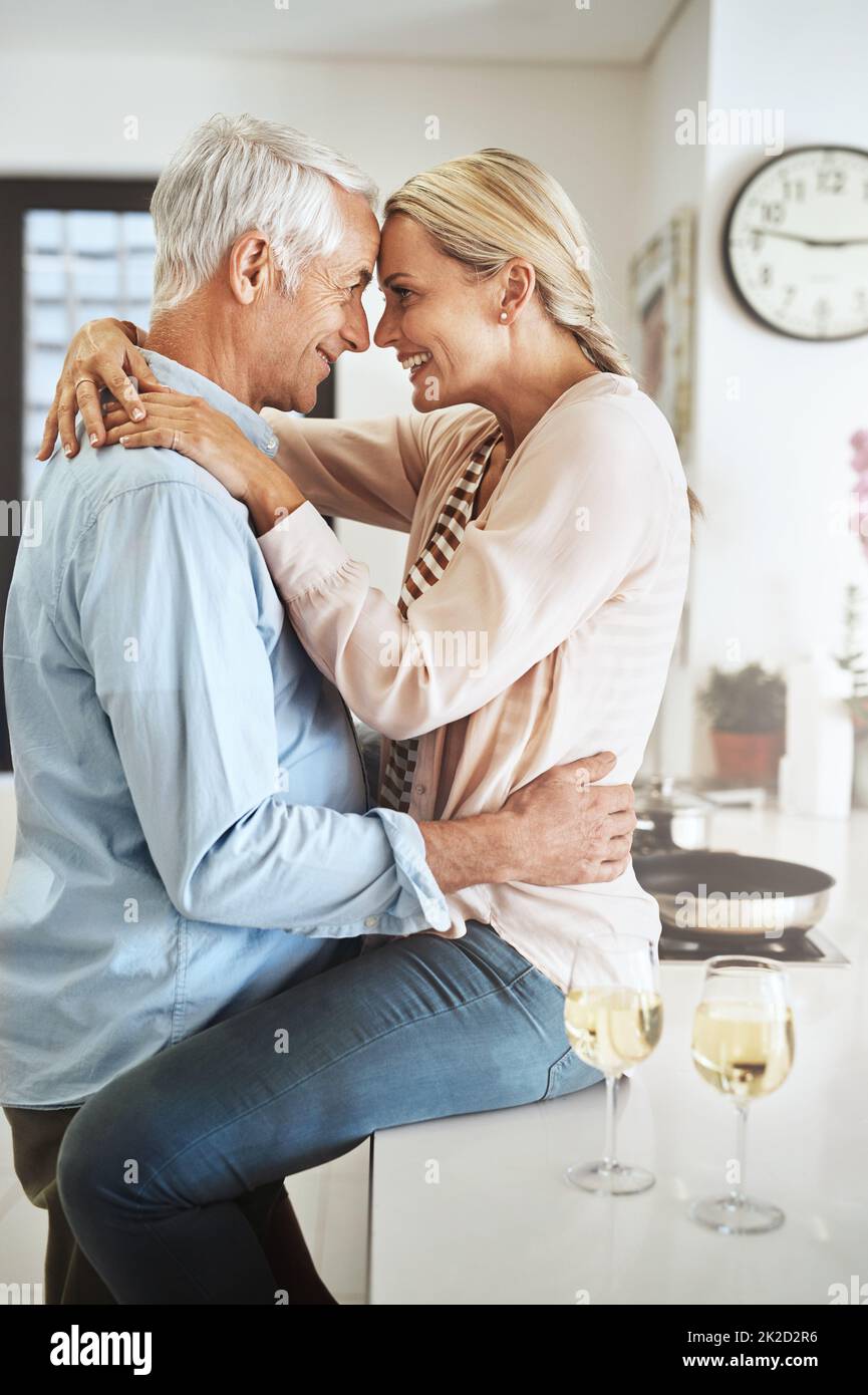 Ihre Liebe wächst jeden Tag. Eine kurze Aufnahme eines liebevollen reiferen Paares, das einen intimen Moment in seiner Küche teilt. Stockfoto