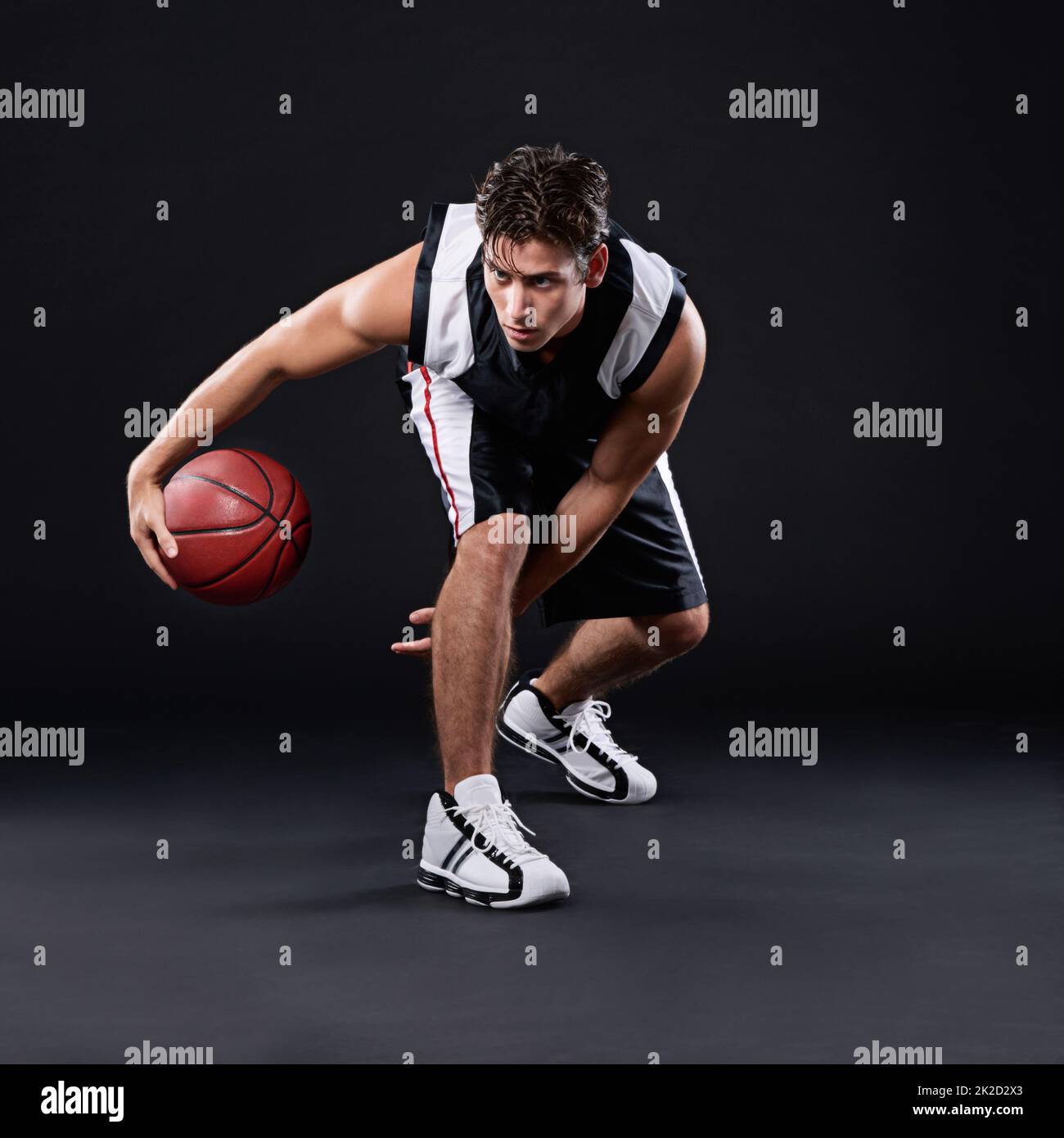 Mit Herz spielen. Ganzkörperaufnahme eines männlichen Basketballspielers in Aktion vor schwarzem Hintergrund. Stockfoto