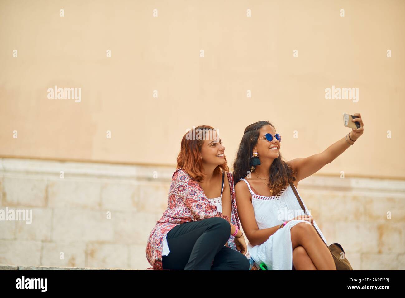 Ein Selfie für jeden Tag unserer Reise. Ausgeschnittene Aufnahme von zwei attraktiven jungen Schwestern, die Selfies in einer fremden Stadt machen. Stockfoto