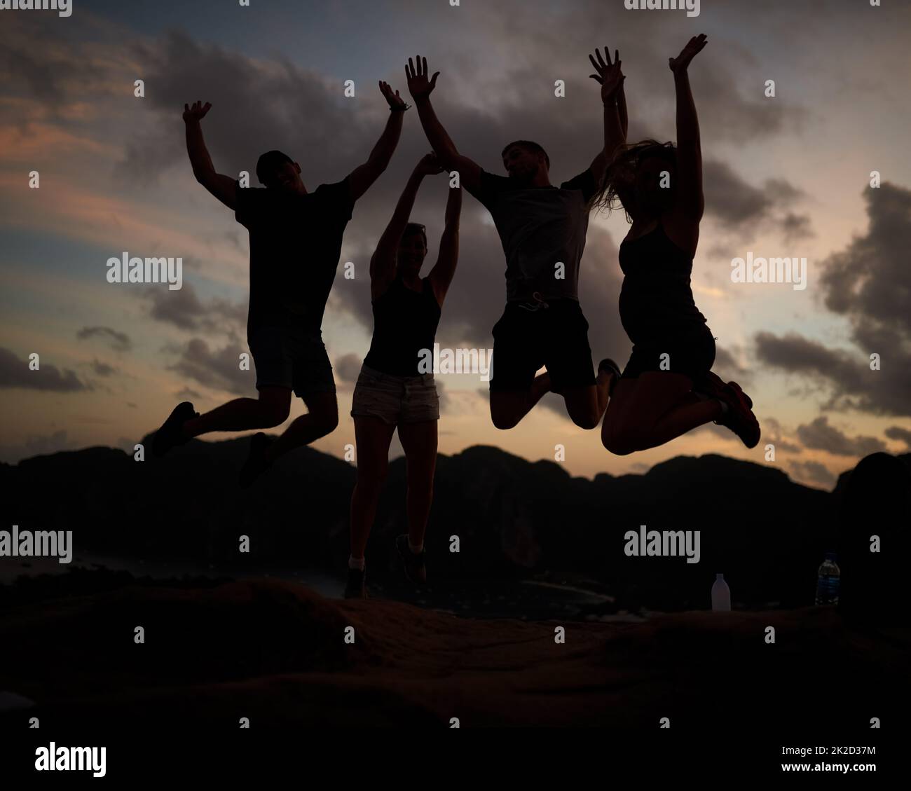 Springen vor Freude. Aufnahme einer Gruppe von springenden Freunden, die gegen einen Sonnenuntergang gedreht wurden. Stockfoto