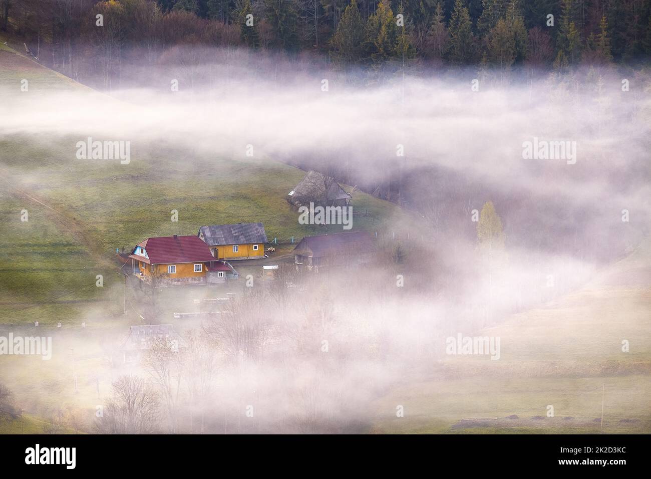 Wunderschöne Frühlingslandschaft. Traditionelles Bergdorf auf Hügeln. Ländlicher ukrainischer Sonnenaufgang in Karpaten. Rauch aus dem Haus Stockfoto