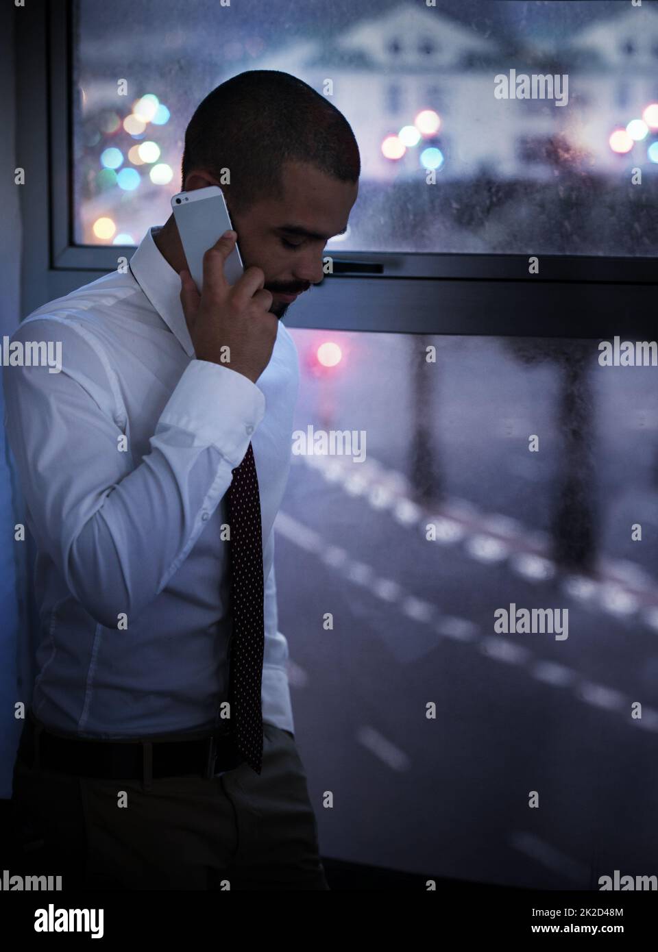 Foto eines Geschäftsmanns, der spät in der Nacht auf seinem Handy spricht. Echte Geschäftsleute wurden vor Ort erschossen. Da es sich bei diesen Standorten um echte Drehorte handelt, die nicht in einem Bürostudio gedreht werden, sind manchmal hohe ISO-Standards erforderlich, um den Moment festzuhalten. Der ISO-Bereich beträgt Stockfoto