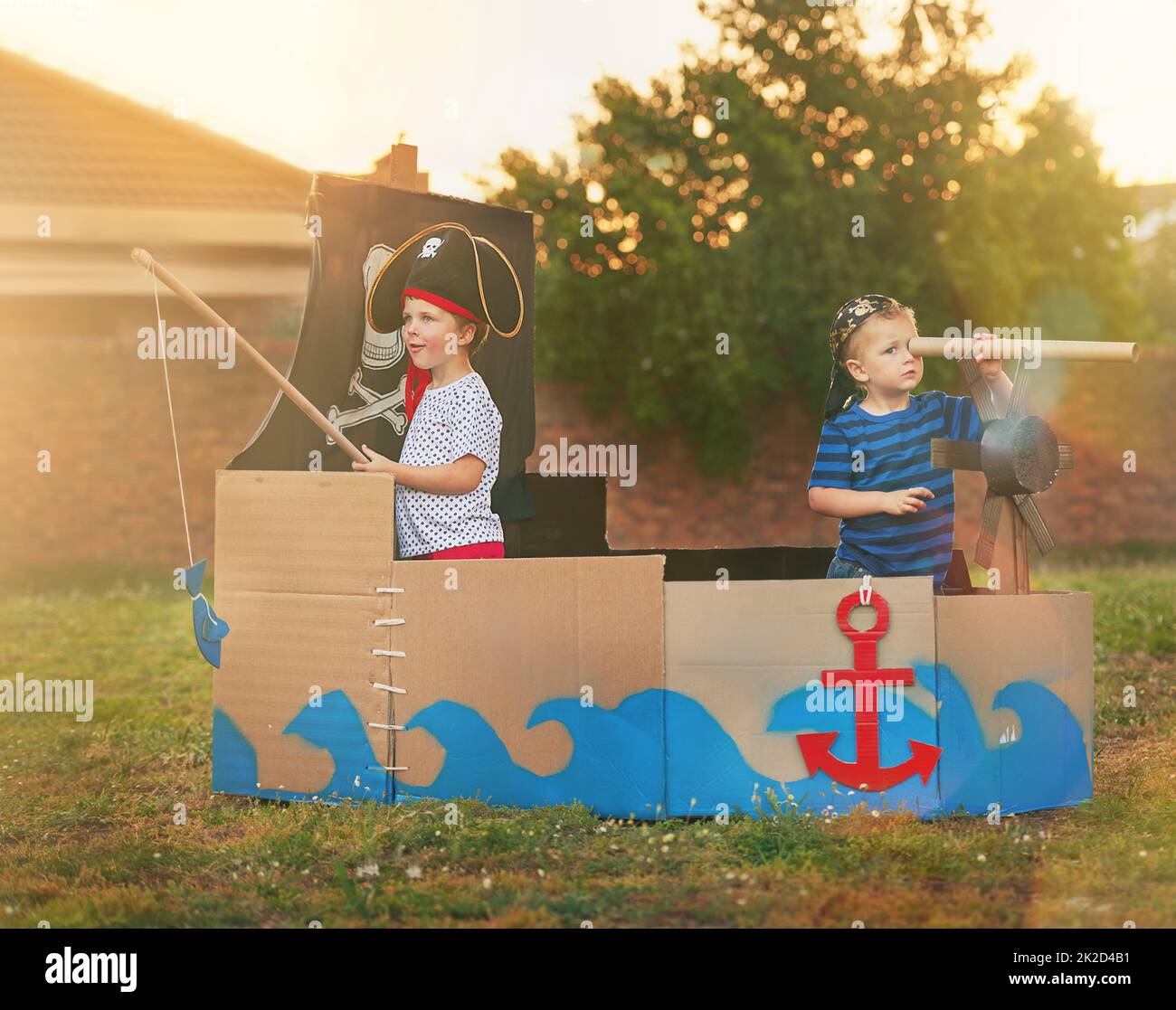 Wer braucht Spielzeug, wenn Sie Phantasie haben. Aufnahme eines niedlichen kleinen Jungen und seines Bruders, der draußen auf einem Boot aus Pappkartons Piraten spielt. Stockfoto
