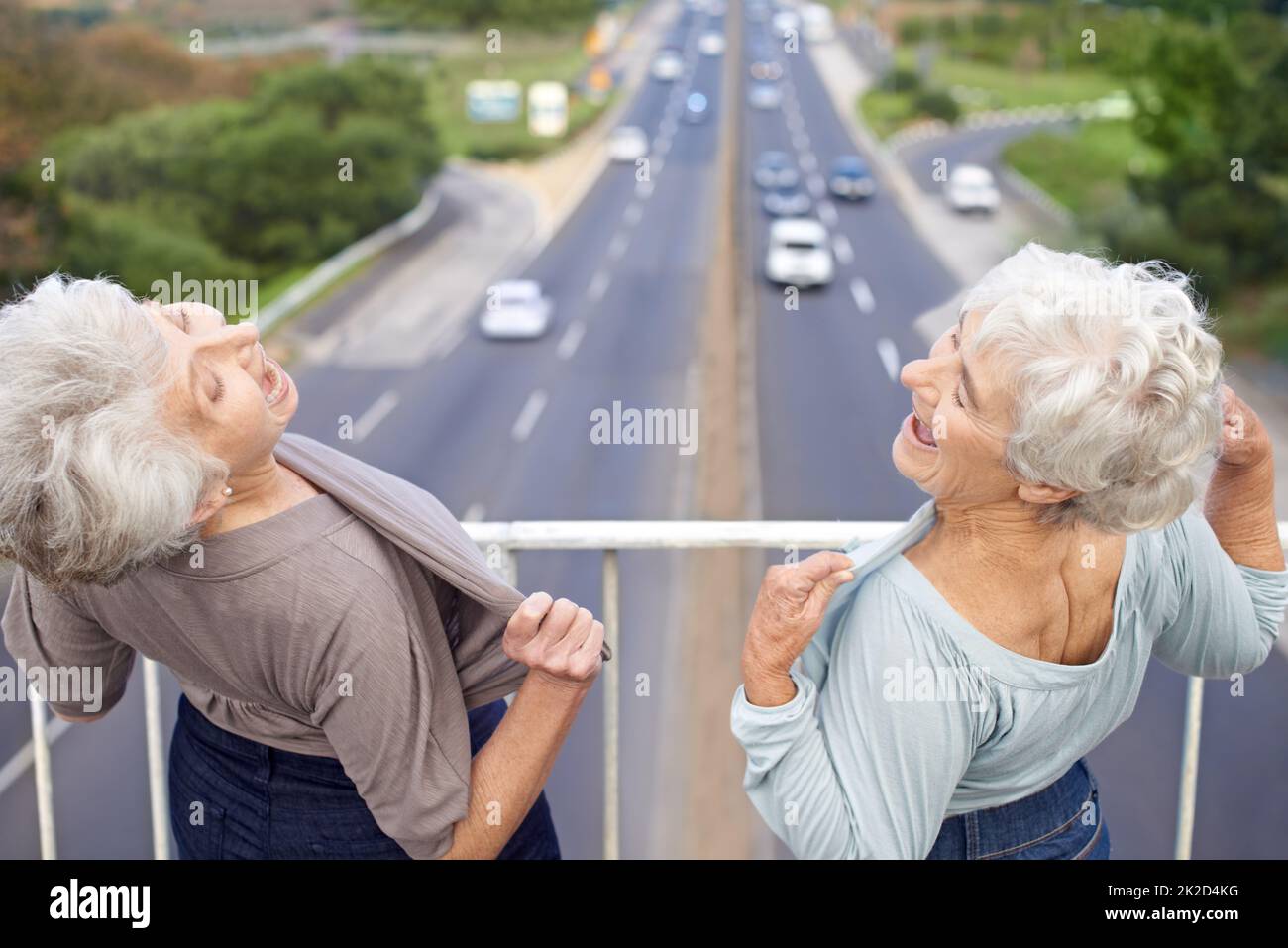 Nie zu alt, um jung zu sein. Zwei ältere Frauen blitzen ihre Brust auf Passanten. Stockfoto