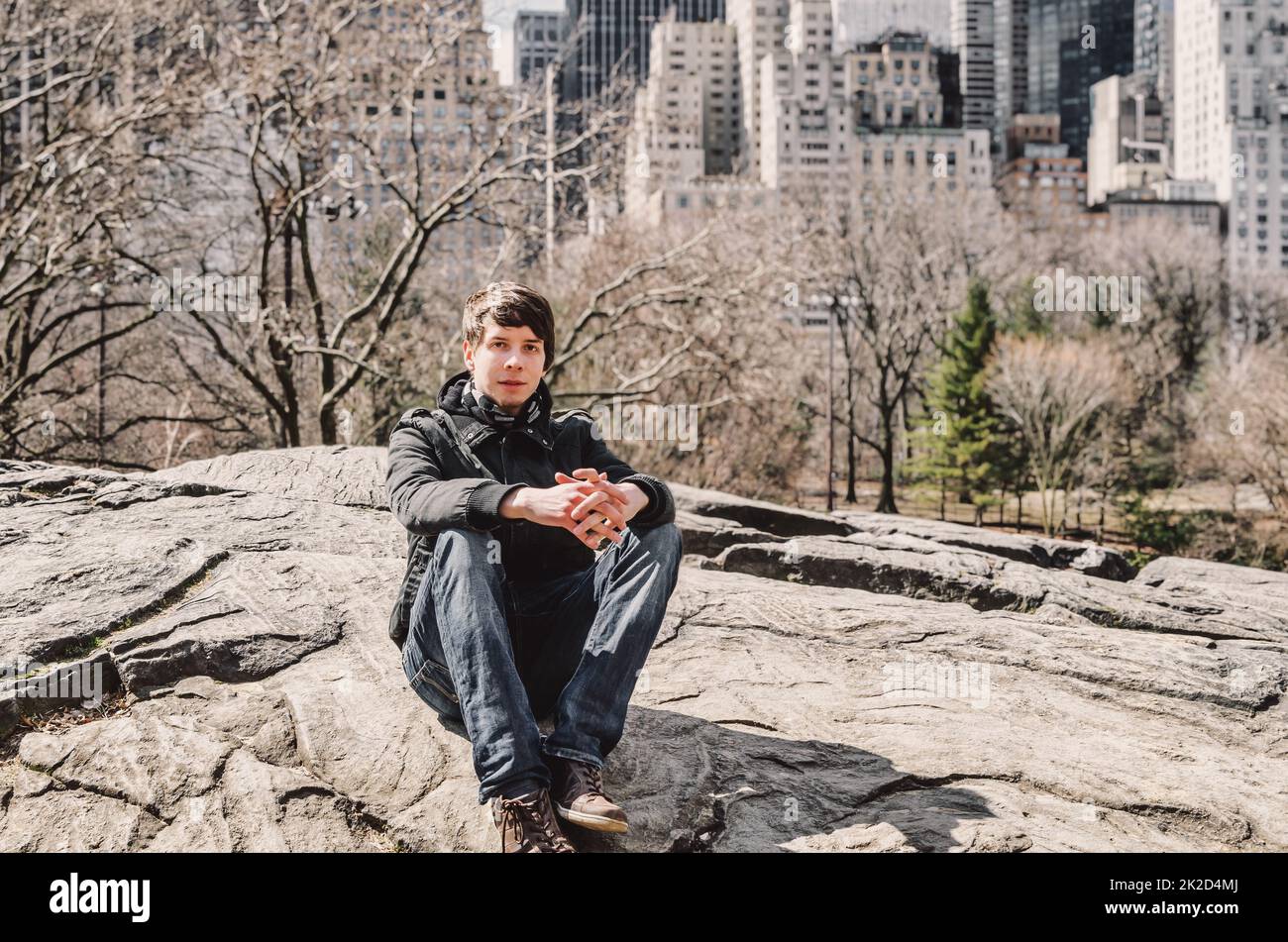 Junger Erwachsener, der im Central Park New york sitzt Stockfoto