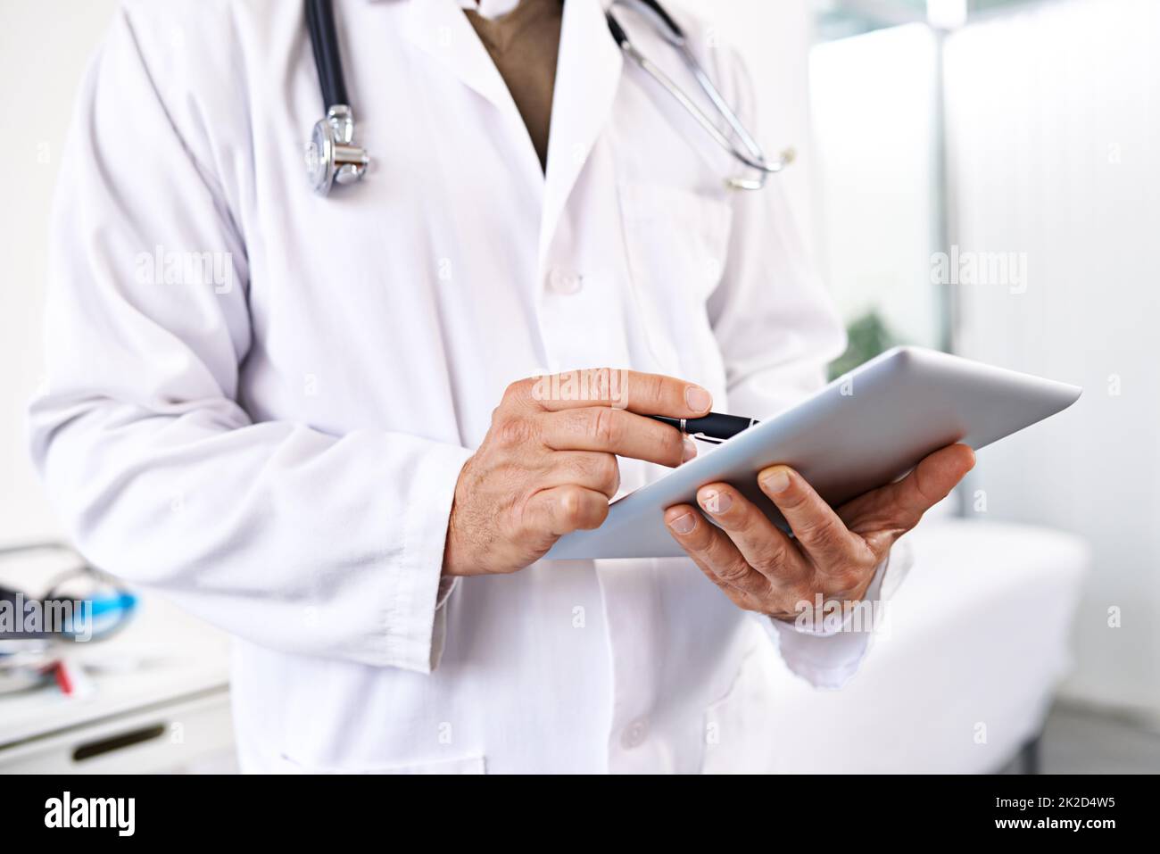 Einfache Aufzeichnung von Patientendaten. Ausgeschnittene Aufnahme eines männlichen Arztes mit einem digitalen Tablet in einem Krankenhaus. Stockfoto