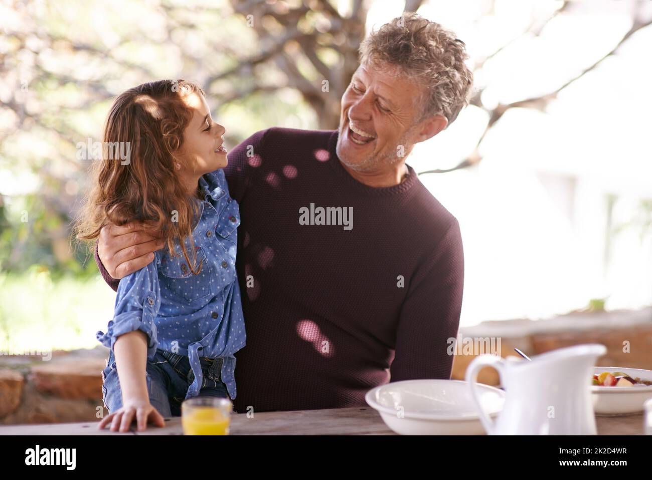 Liebe dich so sehr, mein Liebling. Aufnahme eines kleinen Mädchens und ihres Großvaters beim gemeinsamen Frühstück draußen. Stockfoto