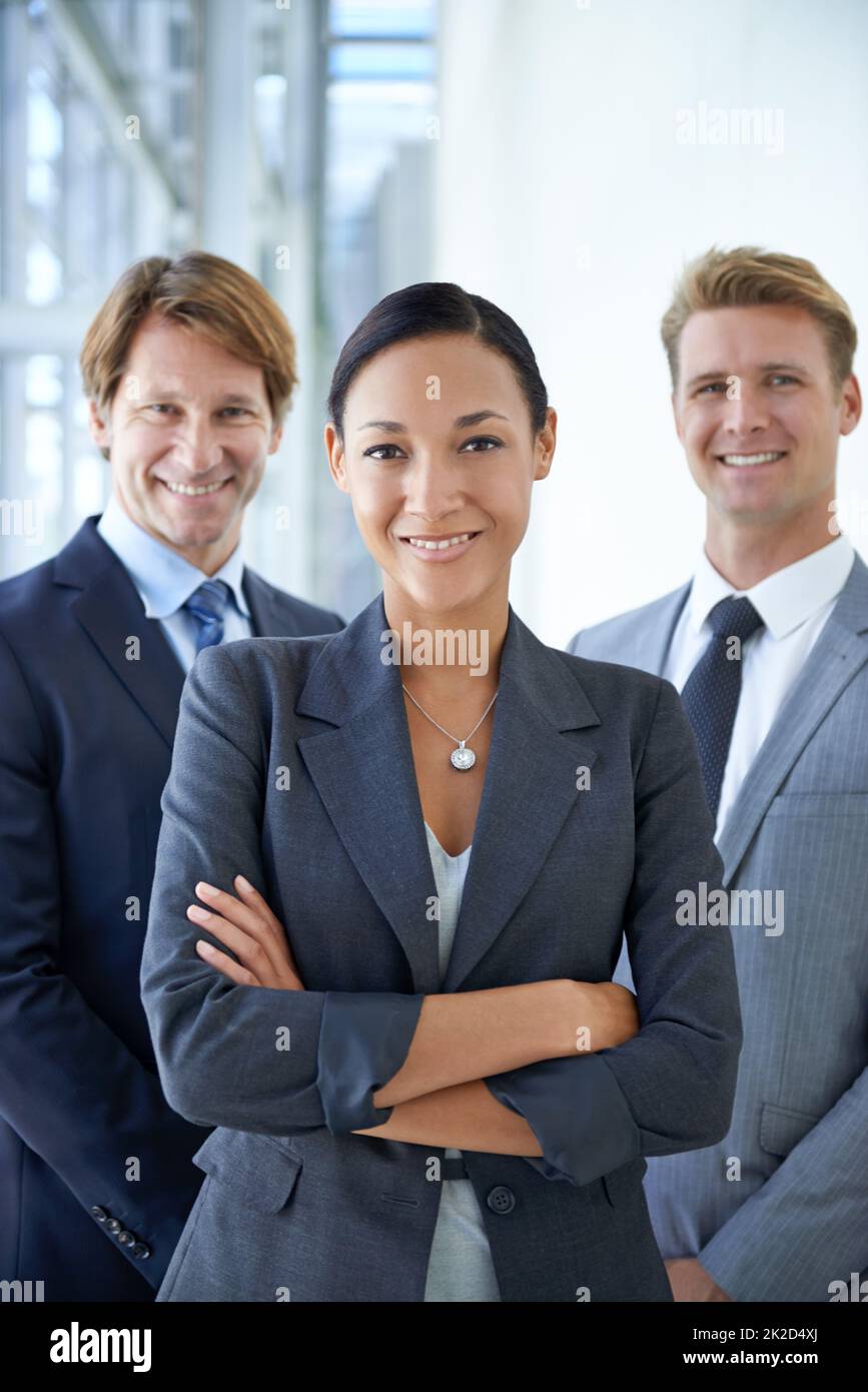 Nichts wird unser Geschäft zurückhalten. Porträt von drei lächelnden Führungskräften, die in einer Bürolobby stehen. Stockfoto
