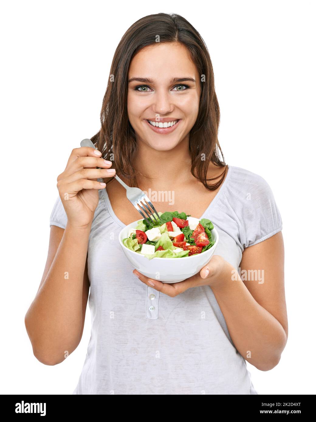 Genießen Sie einen gesunden Snack. Eine junge Frau genießt einen frischen Salat, isoliert auf Weiß. Stockfoto