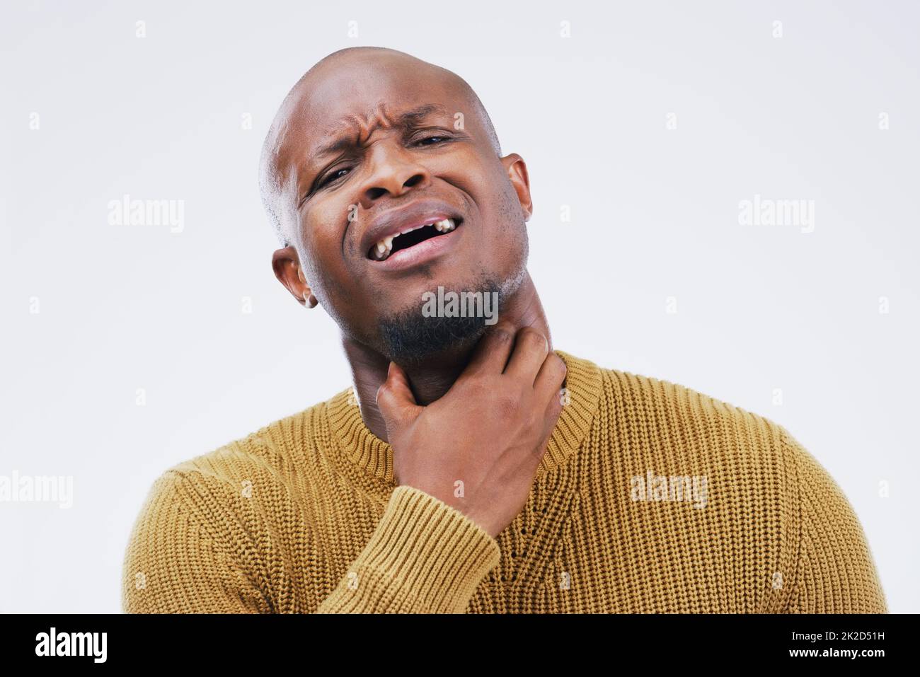 Schreiend vor Schmerzen. Studioaufnahme eines jungen Mannes mit Halsschmerzen vor grauem Hintergrund. Stockfoto