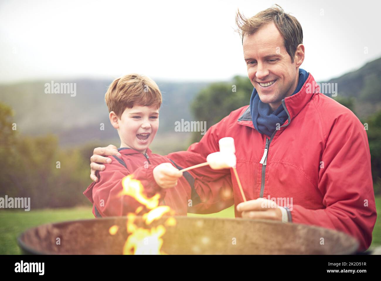 Ich kann es kaum erwarten, sie zu essen. Aufnahme eines Vaters und eines Sohnes, der über dem Feuer Sumpflandschaften rösten. Stockfoto