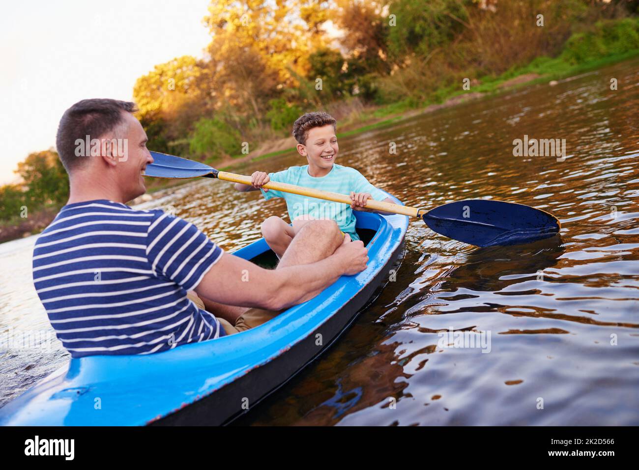 Rudern Sie Ihr Boot. Aufnahme eines Vaters und eines Sohnes, der zusammen auf einem See ein Boot rudert. Stockfoto