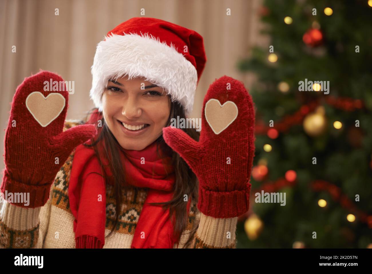 Weihnachtsliebe. Porträt einer attraktiven jungen Frau, die Ihnen ihre Weihnachtshandschuhe zeigt. Stockfoto