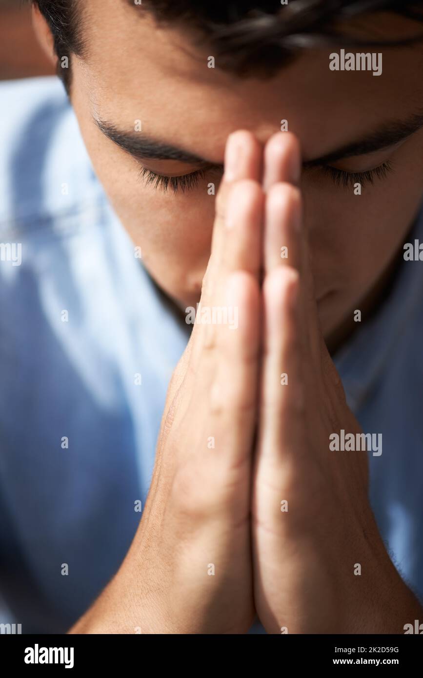 Hoffen und beten. Nahaufnahme eines jungen Mannes, der mit seinen Händen zusammen betet. Stockfoto