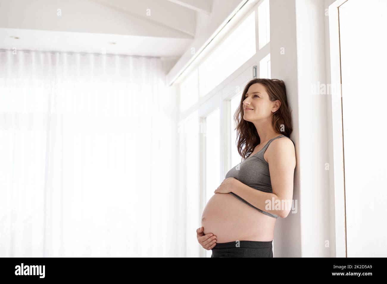 Shes das Bild der Schwangerschaft Gesundheit. Kurzer Schuss einer jungen Schwangeren, die in ihrem Haus steht. Stockfoto