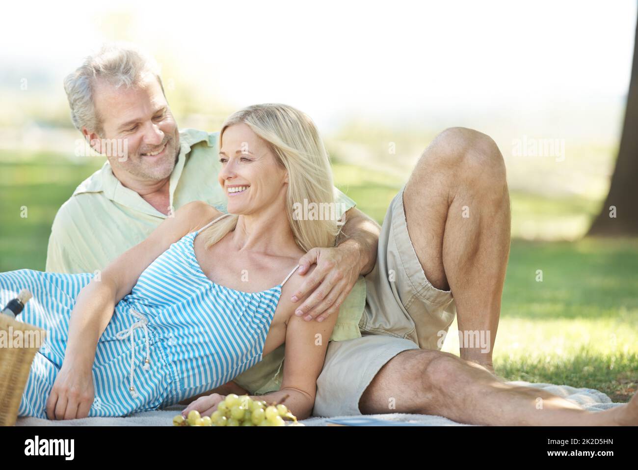 Liebevolle Momente im Freien. Ein lächelnder Ehemann und eine lächelnde Frau genießen ein gemütliches Picknick im Park. Stockfoto