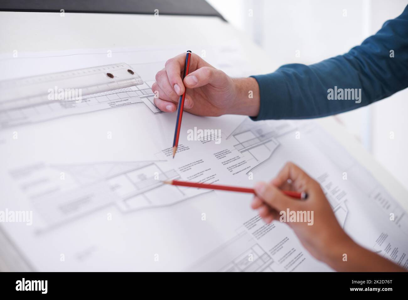 Es geht um Präzision. Ausschnittene Aufnahme von zwei Architekten, die an einem Reißbrett an einem Bauplan arbeiten. Stockfoto