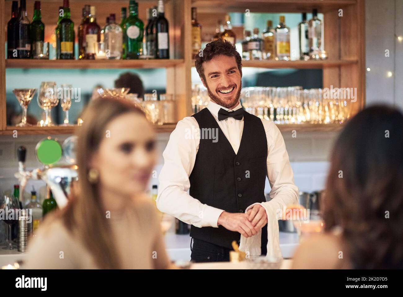 Er liebt seinen Job einfach. Eine kleine Aufnahme eines hübschen jungen Kellners, der lächelt, während er in einer Bar steht. Stockfoto