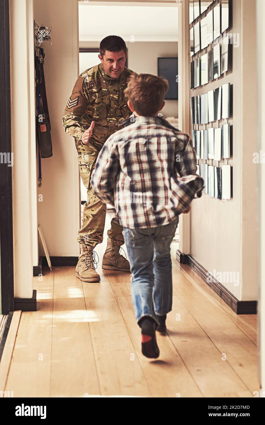 Raten Sie mal, wer nach Hause kommt. Rückansicht eines kleinen Jungen, der seinen Vater begrüßt, als er aus der Armee zurückkehrt. Stockfoto