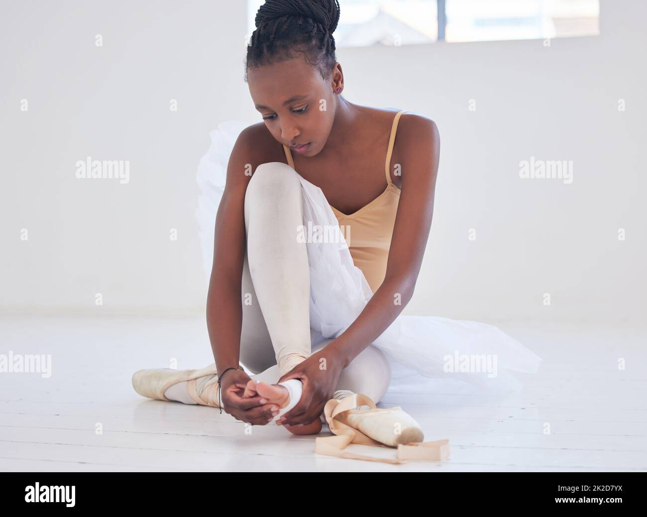 Ein Preis der Künste. Aufnahme einer jungen Balletttänzerin, die ihre spitzenschuhe festbindet. Stockfoto