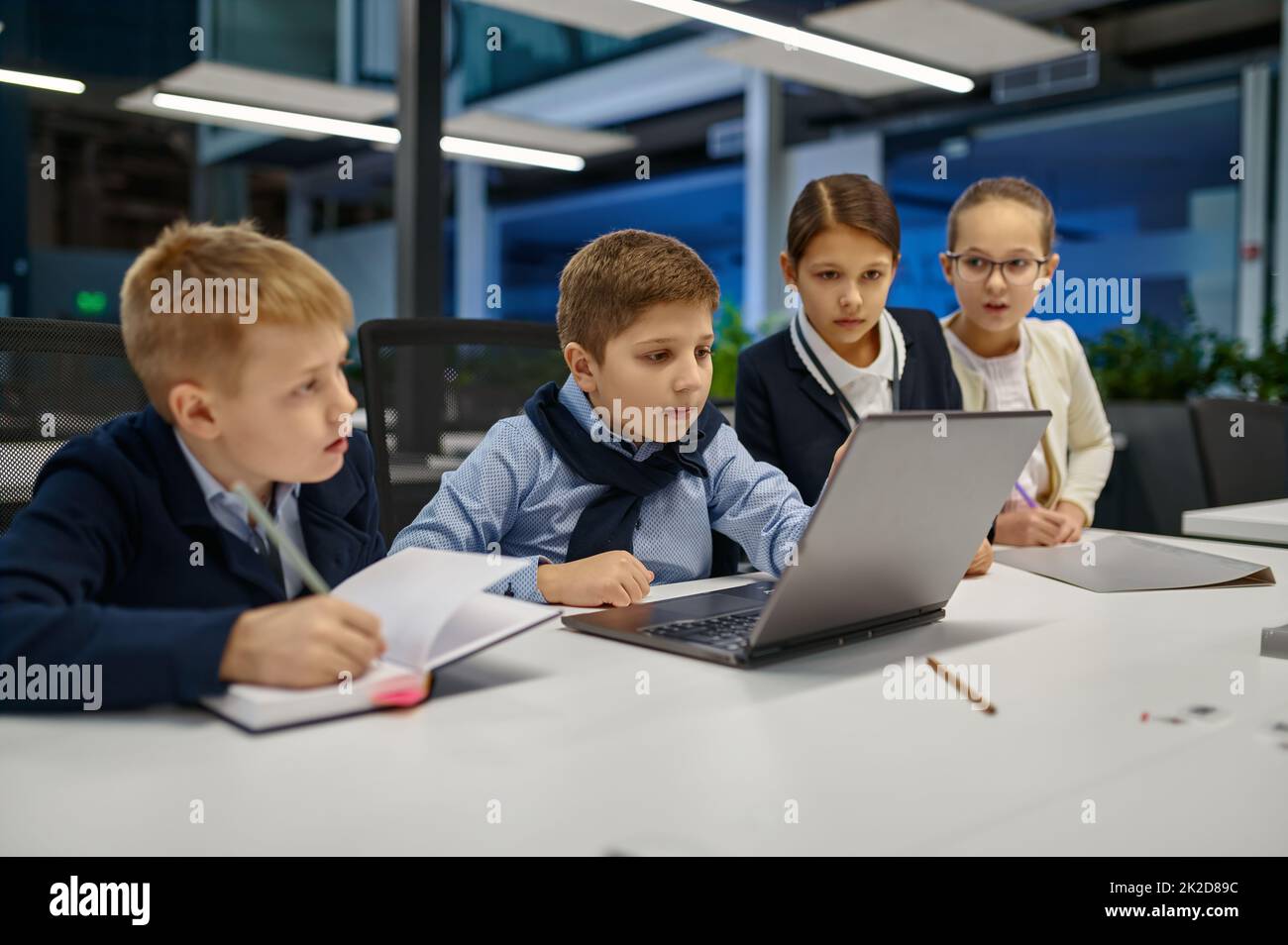 Kinder, die auf den Laptop-Bildschirm schauen, diskutieren etwas Stockfoto