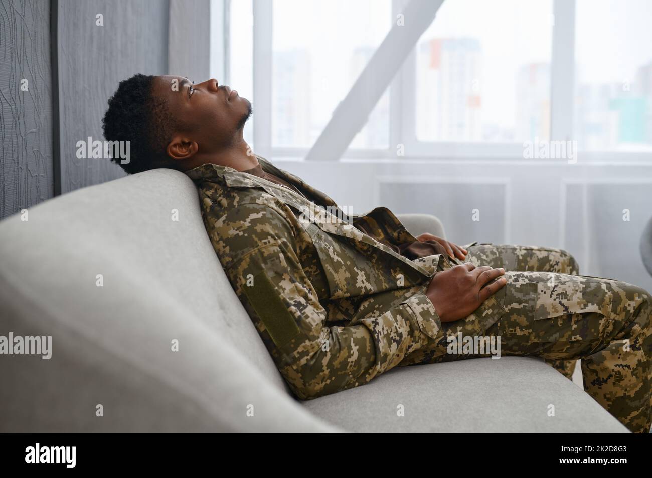Deprimierter Soldat in Uniform sitzt auf der Couch Stockfoto