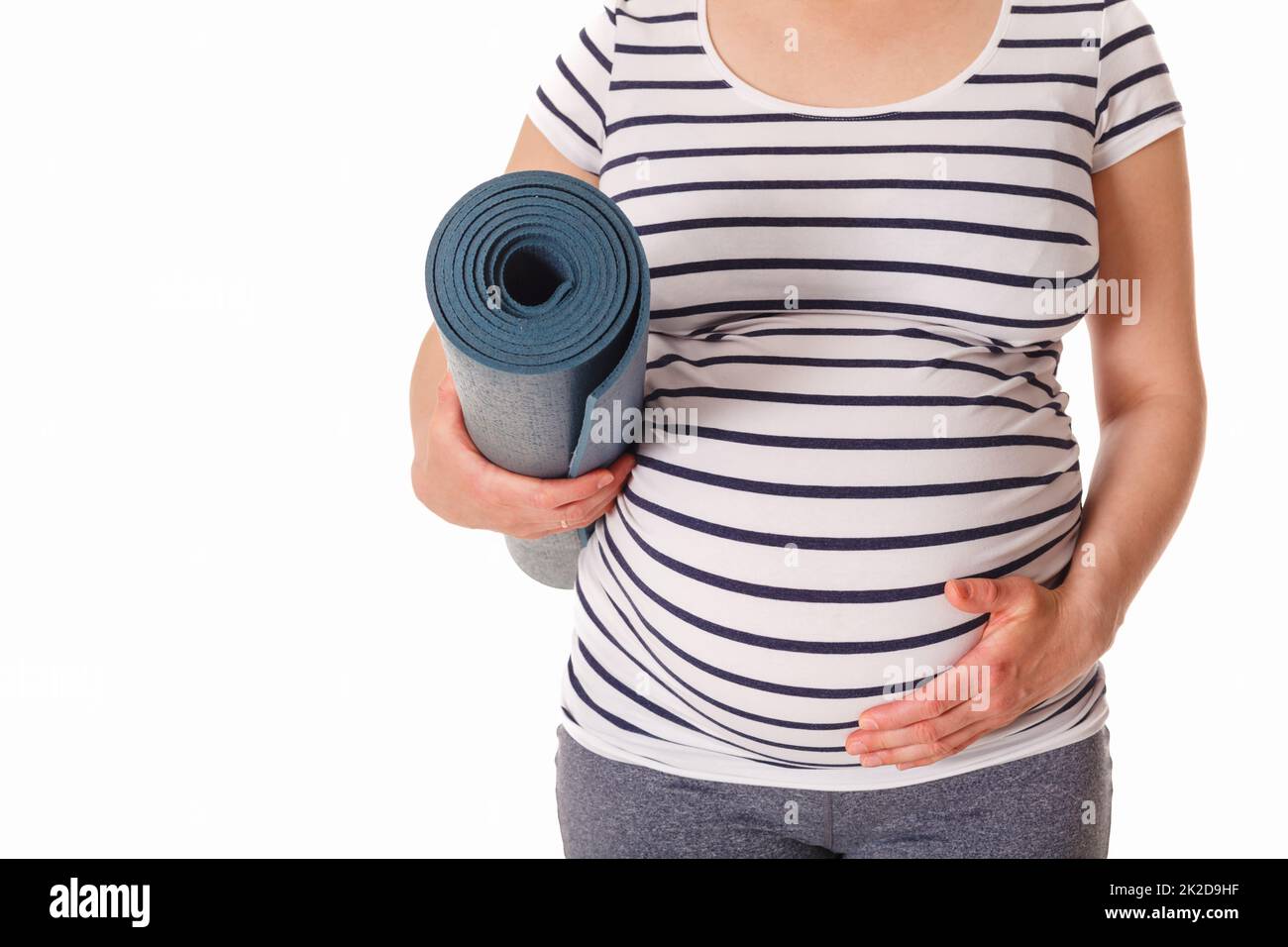 Schwangerin steht mit Yogamatte Stockfoto
